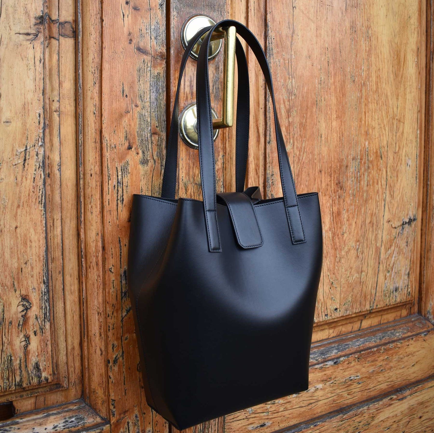 black leather tote bag on gold door handle