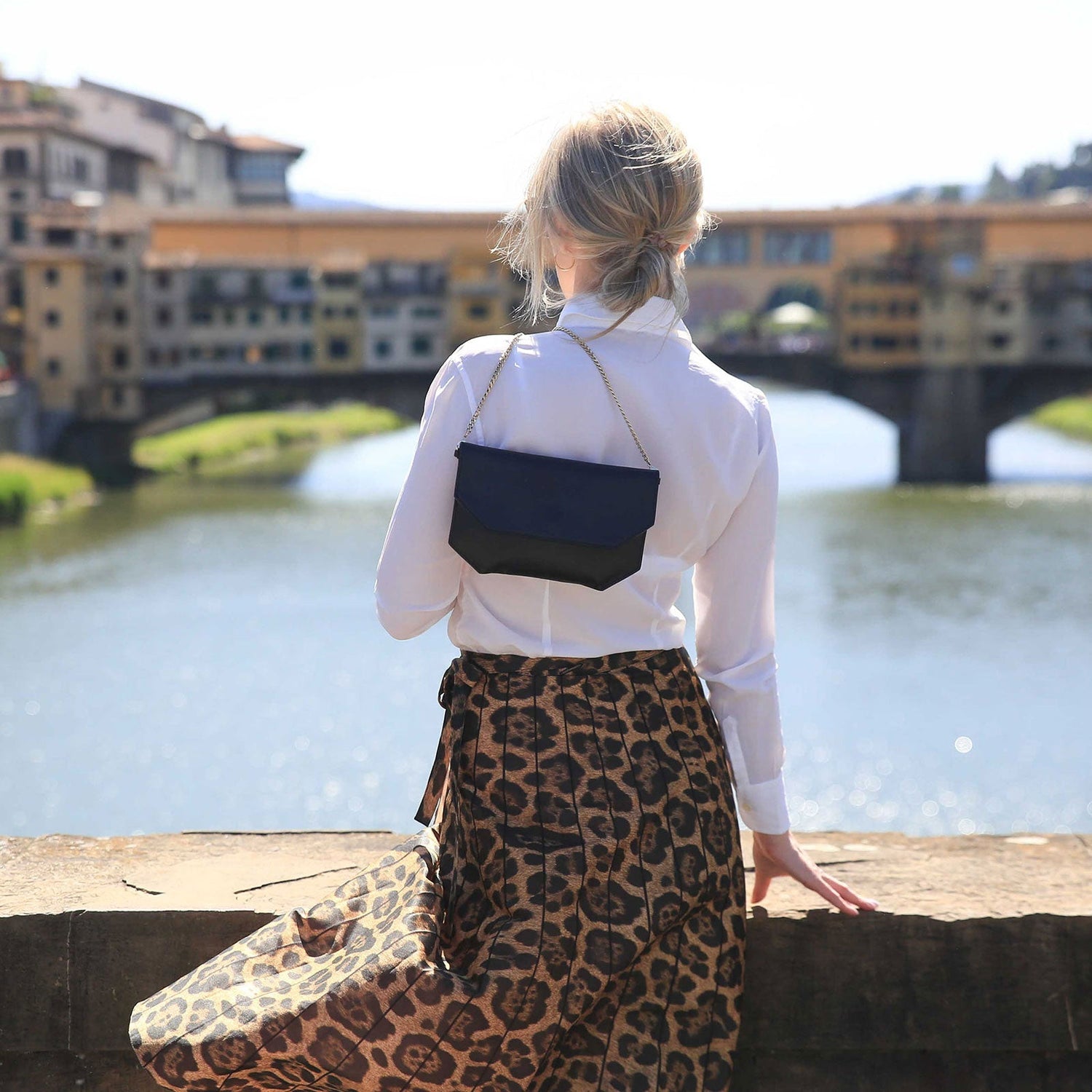 CHANDRA KEYSER Andiamo black evening bag, made in Italy. Model standing on Ponte Vecchio Bridge in Florence, Italy.