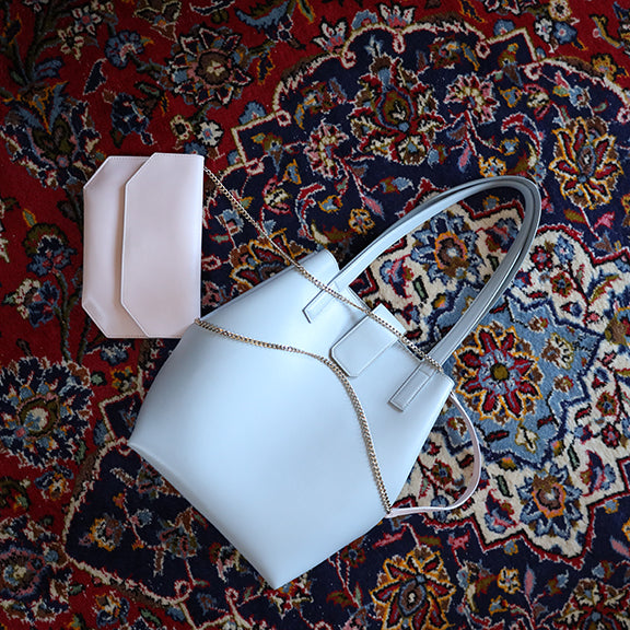CHANDRA KEYSER Andiamo Clutch bag and La Borsa structured tote bag, made in Italy. The grey leather bucket bag and light pink chain crossbody bag laying on a rug