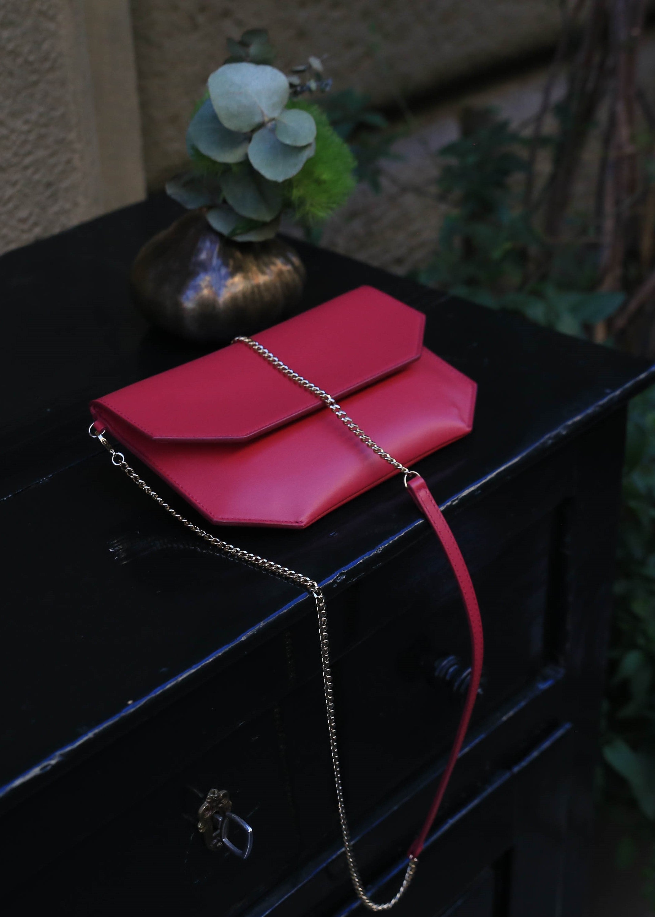 Chandra Keyser Fuchsia Bright Pink Crossbody Clutch Purse. Andiamo Purse. Sustainable Luxury Made in Italy. Sitting on a black wooden table.