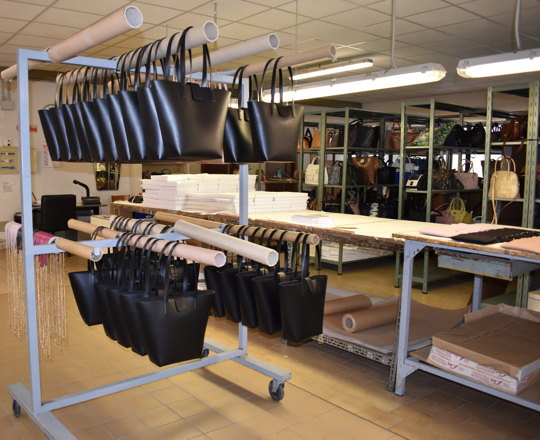 Inside the family owned Italian factory in Tuscany, with black tote bags ready for packaging. Chandra Keyser La Borsa Black Leather Shoulder Bag.