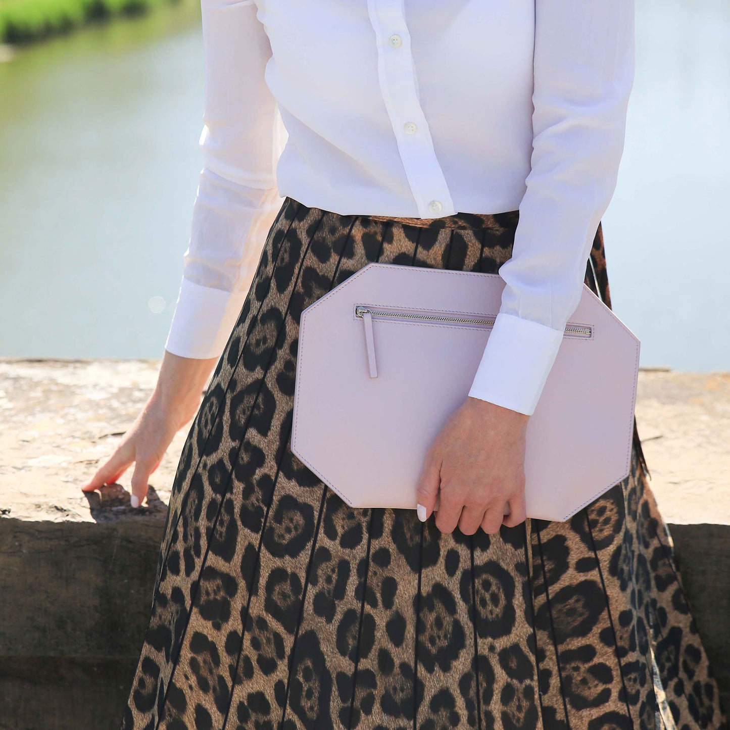 Pink smooth matte leather clutch, complementing animal print silk skirt. minimalist clutch quiet luxury Firenze clutch by Chandra Keyser