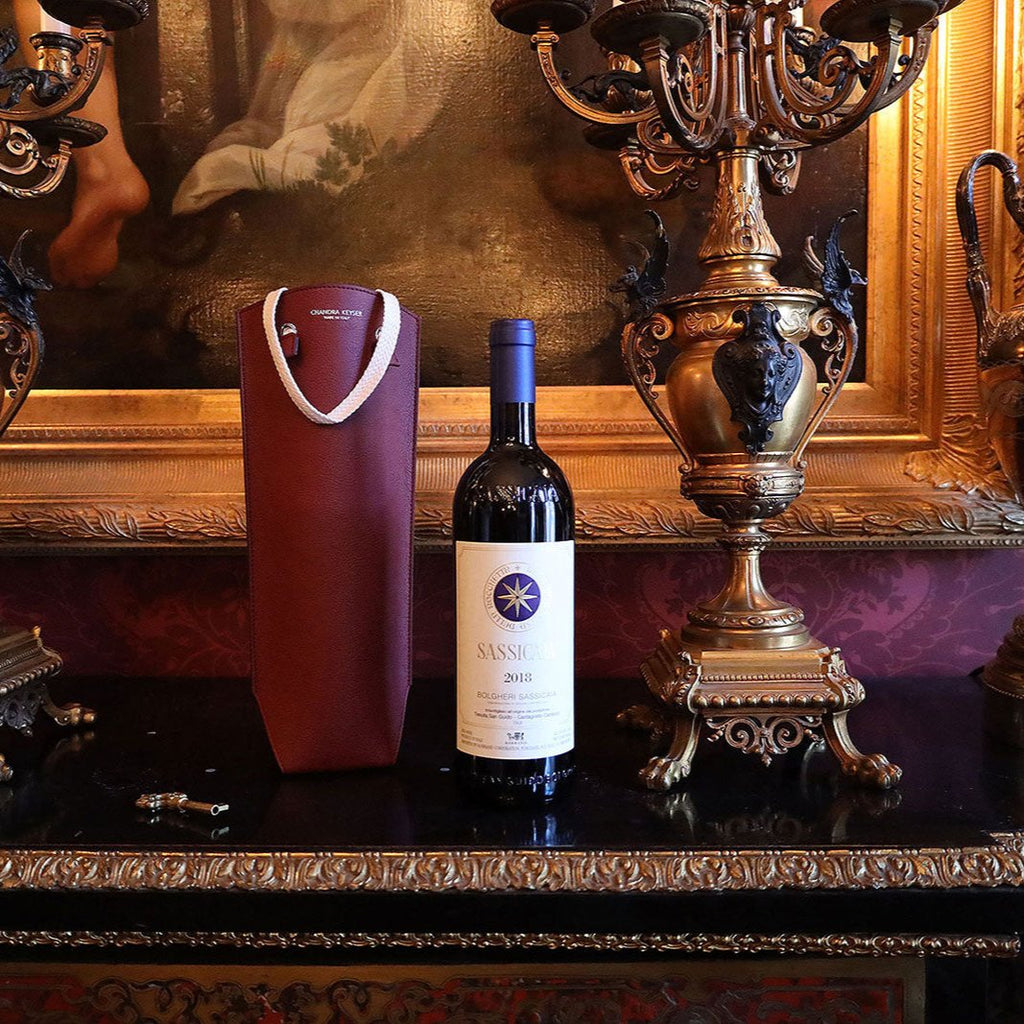 Sustainable Luxury Gift by CHANDRA KEYSER La Borsa Da Vino, Vegan Leather Red Wine Bag Made in Italy, next to Sassicaia Wine. Zero-waste luxury bag.