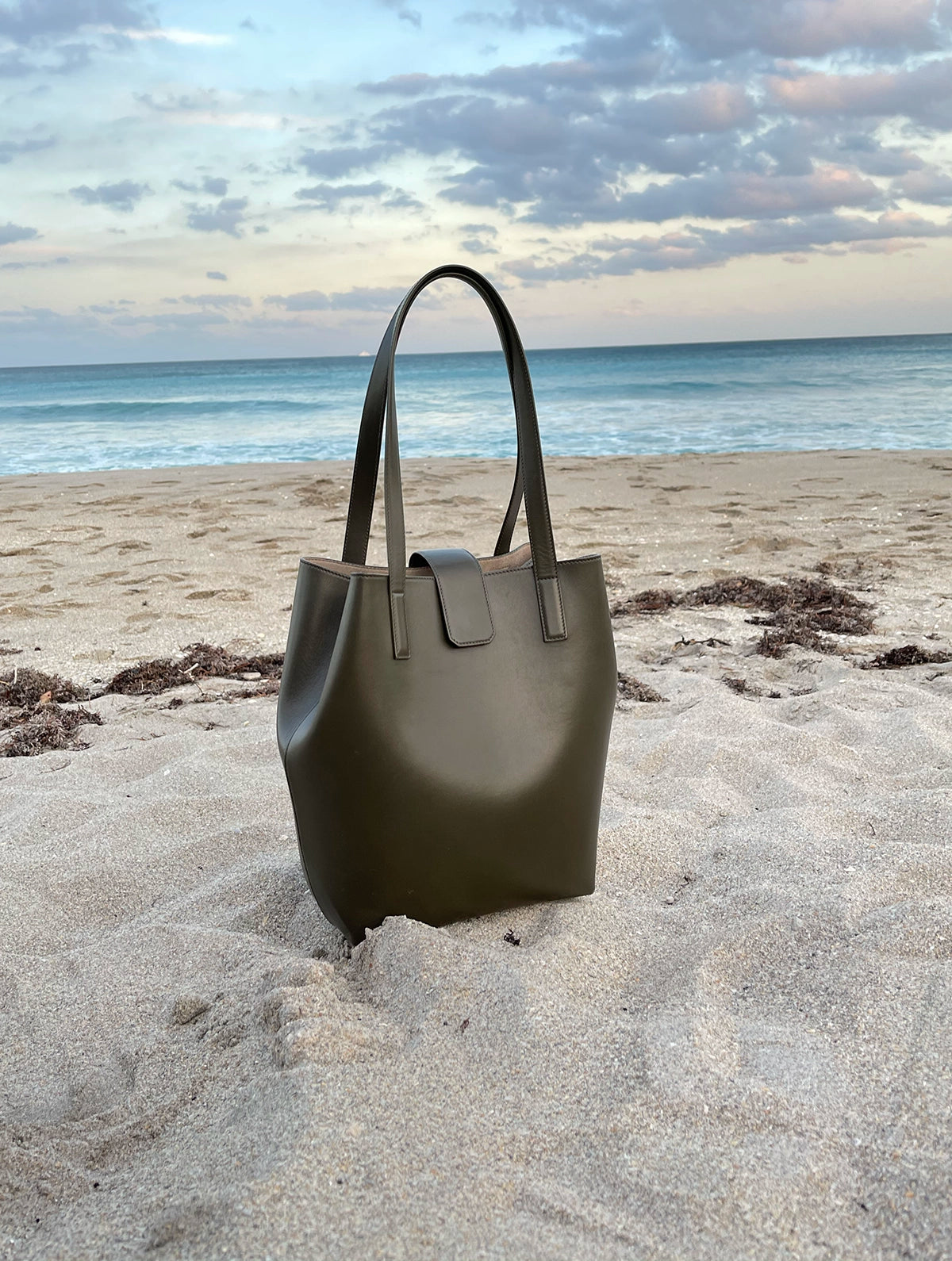 Luxury Green Bag sitting on the beach, military green smooth matte leather, medium shoulder bag by Chandra Keyser